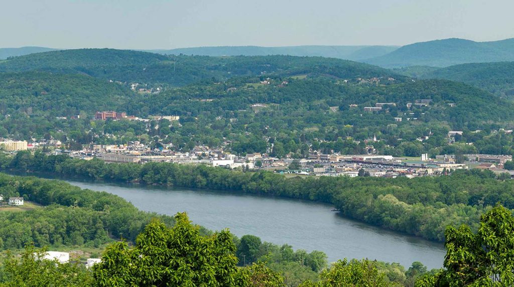 Aerial view of the Williamsport, PA area featuring hills, a community, and a river.