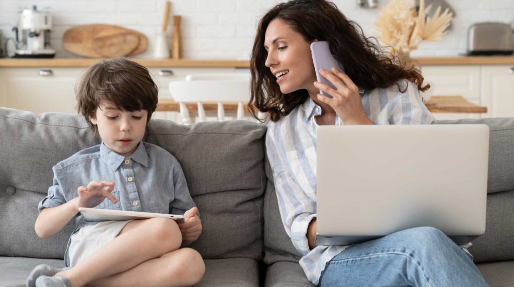 Mother and son sitting on the couch, each looking at their devices with mom checking the firewall update
