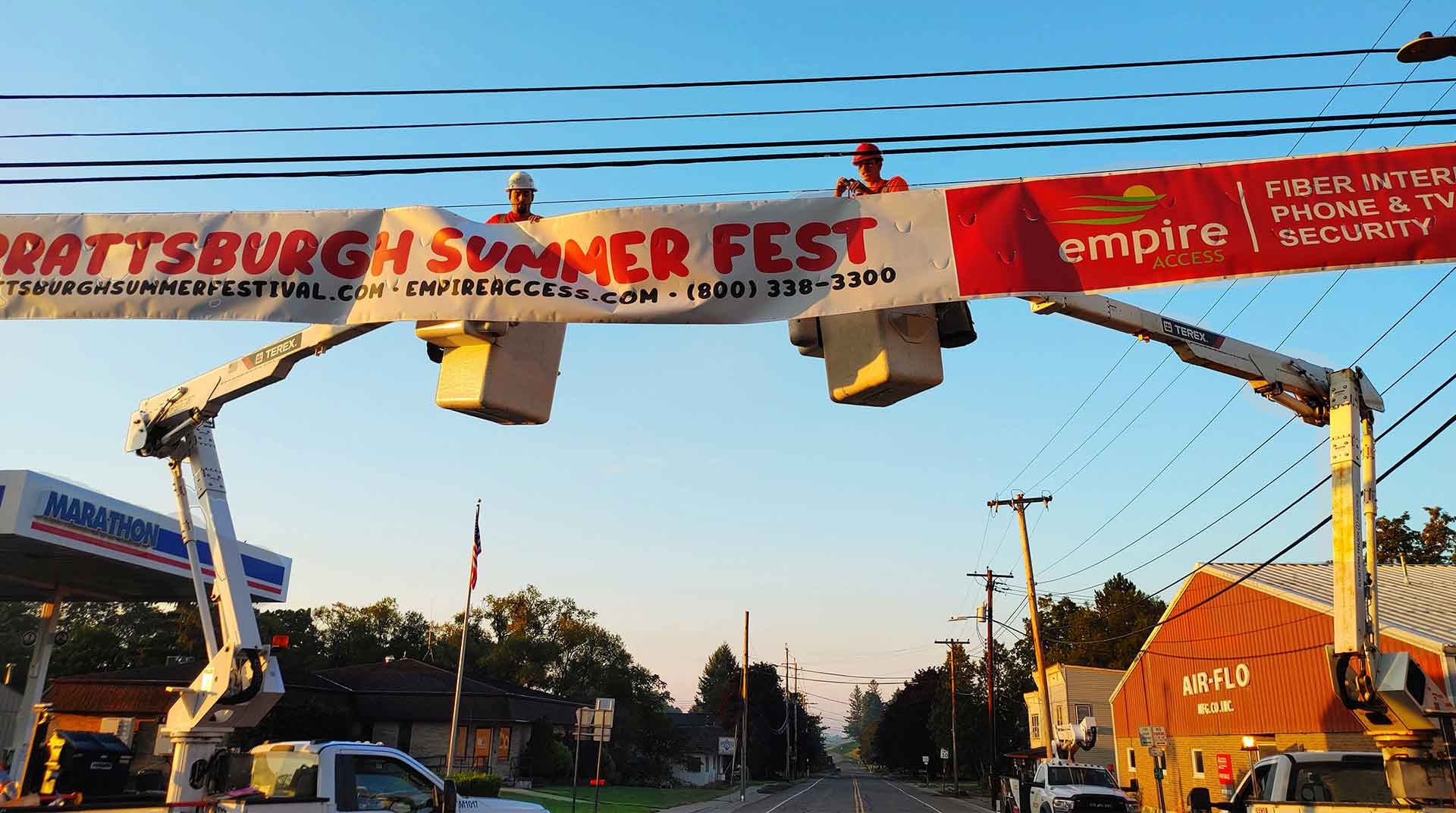 Empire Access employees using equipment to install a community banner in Prattsburgh, NY demonstrating who Empire Fiber Internet is.
