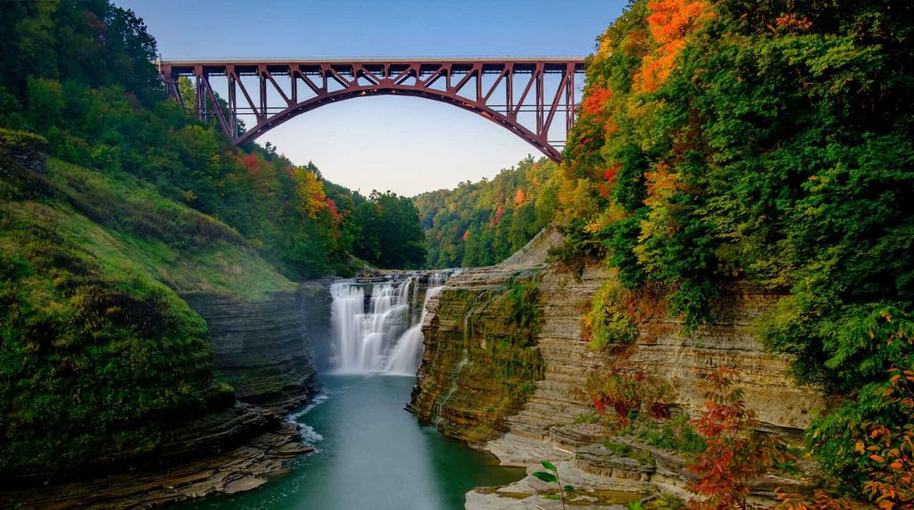 View of the upper waterfalls and railroad bridge at Letchworth State Park during the autumn season