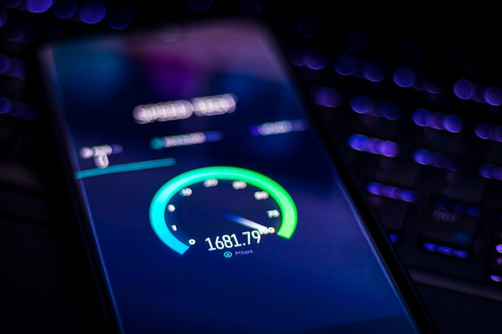 Close-up of a smartphone screen displaying an internet speed test result, indicating a blazing download speed of 1681.79 Mbps. The blurred purple and blue lights in the background hint at a digital setting, perfect for troubleshooting any connectivity issues.