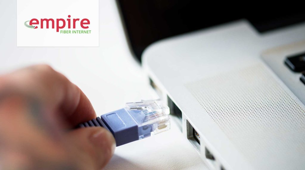 closeup of person hand plugging ethernet cable into a laptop