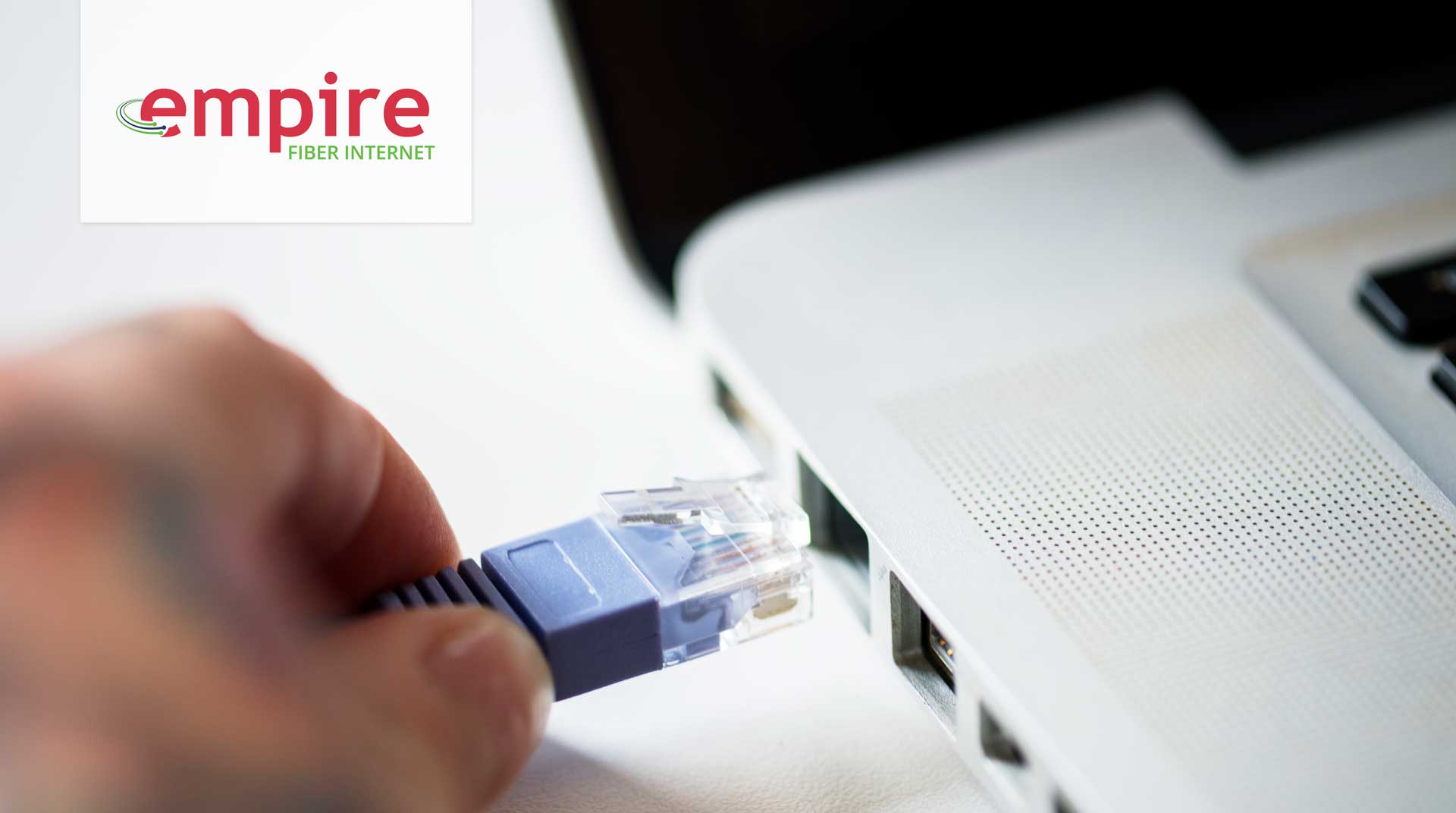 closeup of person hand plugging ethernet cable into a laptop
