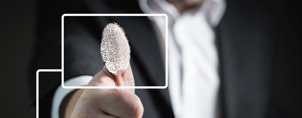 A person in a suit presses their thumb against a transparent surface, highlighting a digital fingerprint. Empire Access Security ensures that every touch is encrypted and secure, with the focus on the thumb and fingerprint while the background remains slightly blurred.