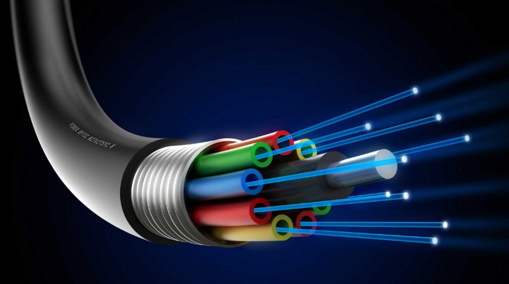 Close-up of a cut-open fiber optic cable against a dark blue background. The cable shows multiple colorful internal wires and glowing blue light beams extending outward, illustrating data transmission.