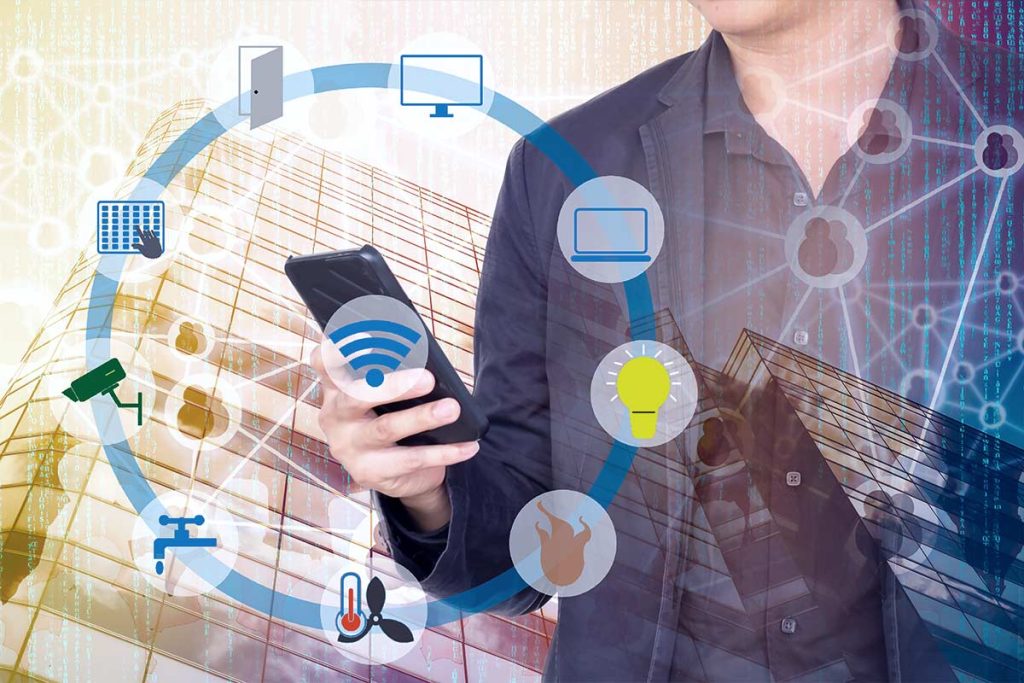 A person in a suit holds a smartphone, surrounded by smart device icons such as a desktop, laptop, thermostat, lock, light bulb, and security camera, symbolizing connectivity and smart technology integration.