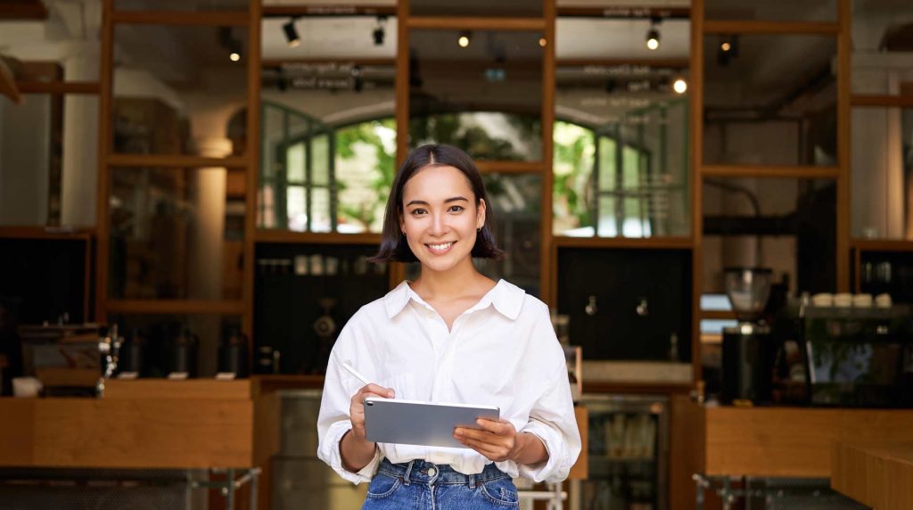 Business owner holding a tablet in front of her business