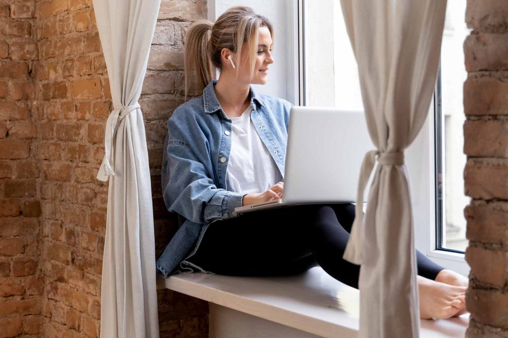 Woman sitting in her apartment using her laptop for a video chat with her family