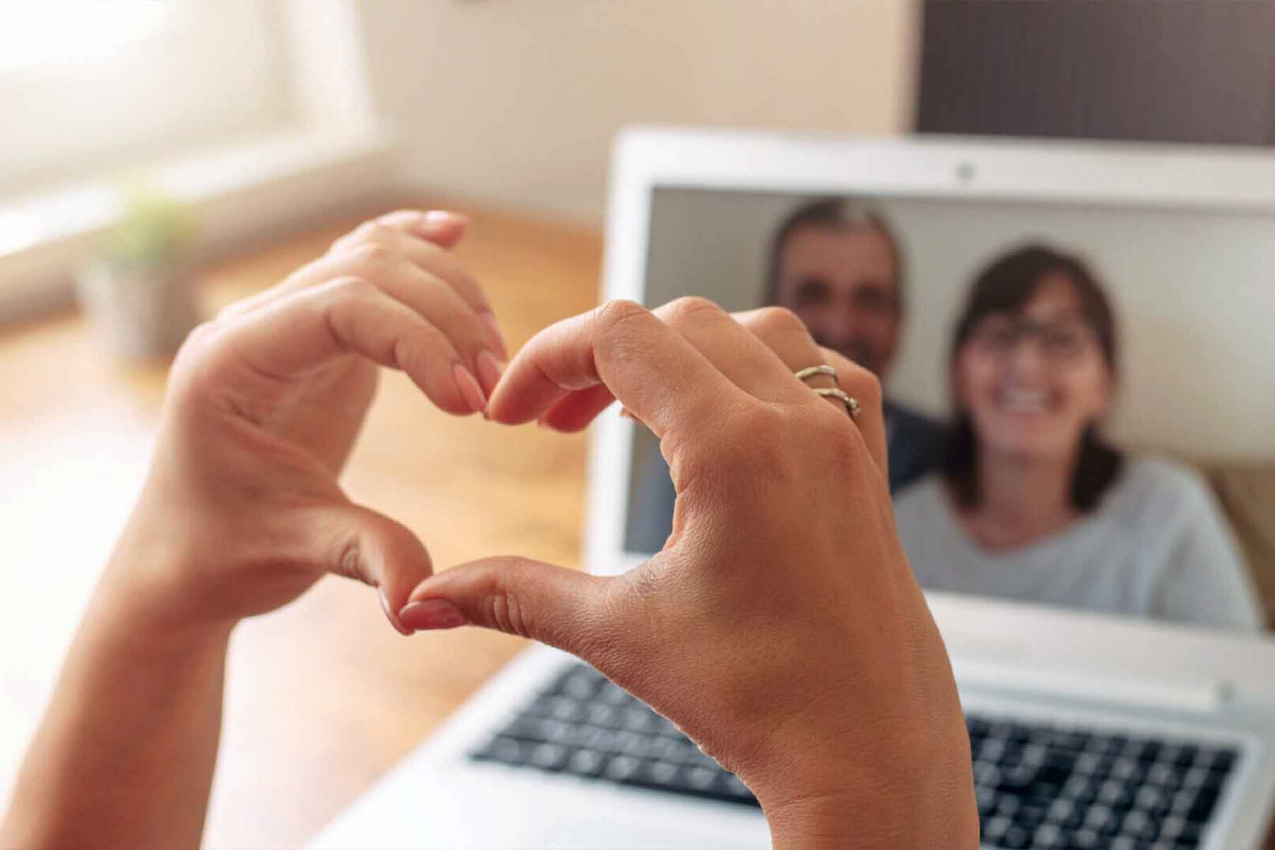 Woman's hands making a heart during a video chat using her laptop, connecting with a purpose
