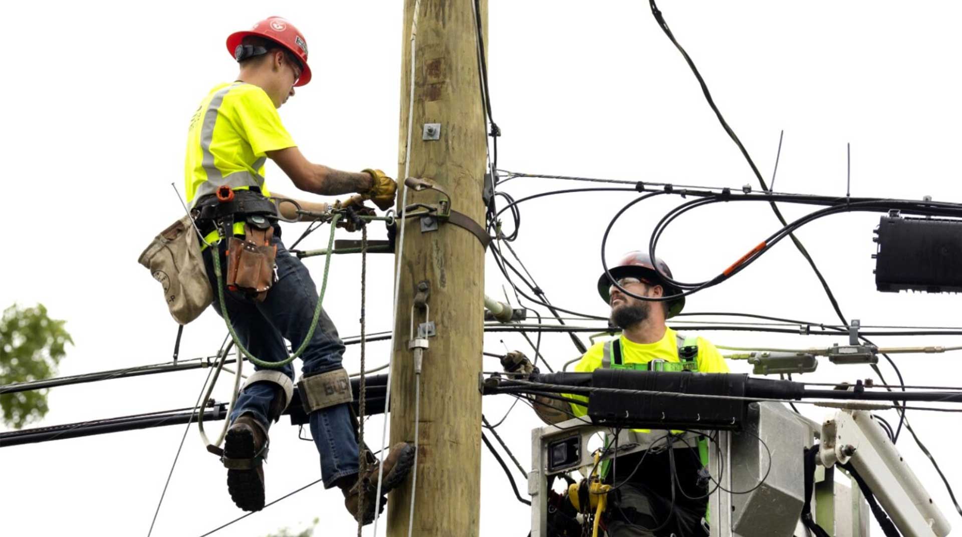 Two Empire Fiber Internet employees working on an utility pole working to restore an internet outage